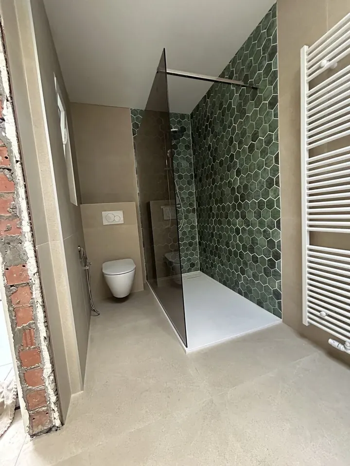 Gerenoveerde badkamer met groene hexagon-tegels in de inloopdouche